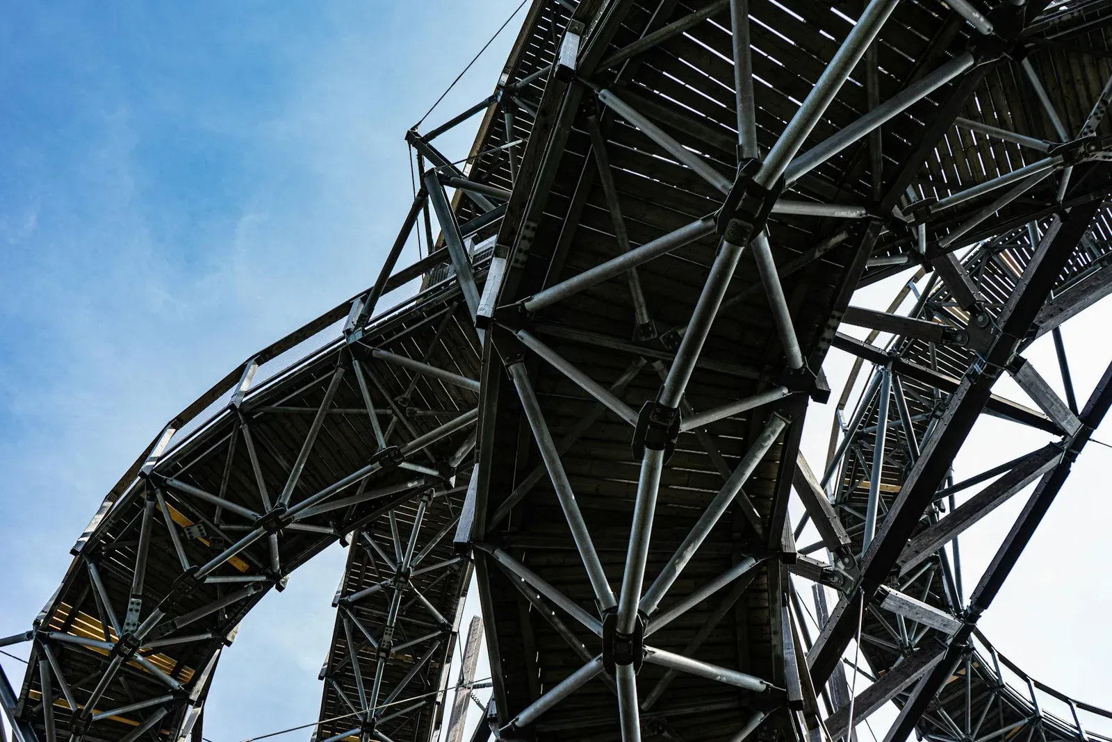 Dynamic view of the steel structure of the Dolní Morava Sky Walk against a clear sky.