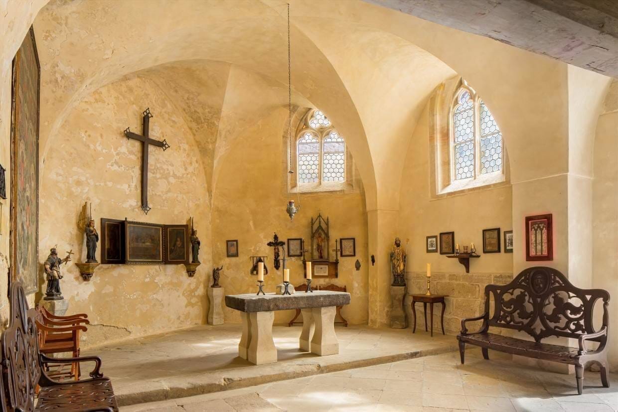 The historic interior of Kost Castle's chapel with its Gothic vaulted ceiling.