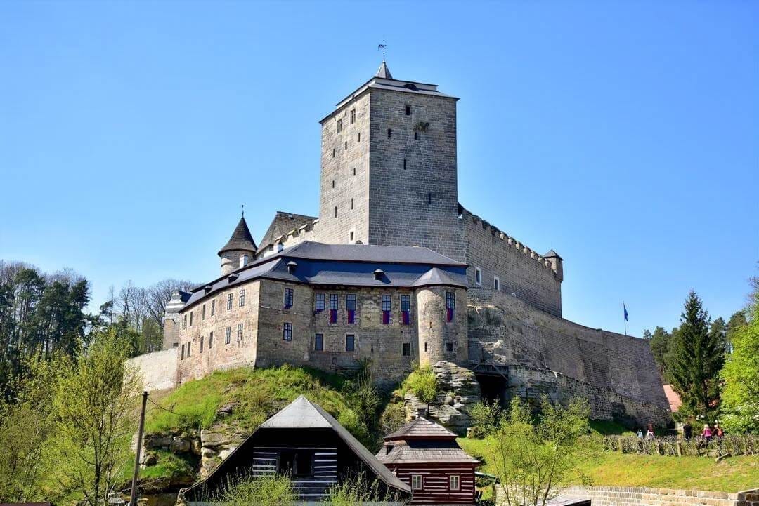 The unique trapezoidal White Tower of Kost Castle against a blue sky.