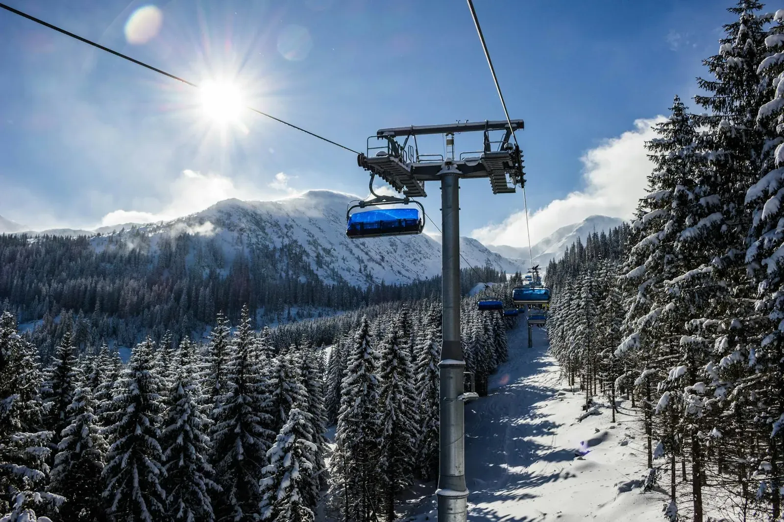 Scenic view of a ski lift in the snowy mountains of Zuberec, Slovakia under a bright winter sun.