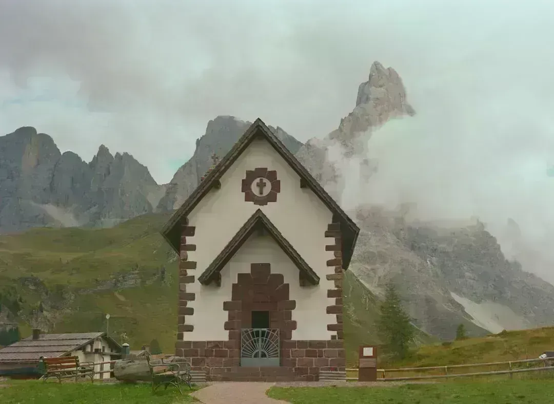 Chapel in the Dolomites, Italy, under cloudy skies, capturing serene autumn morning vibes.