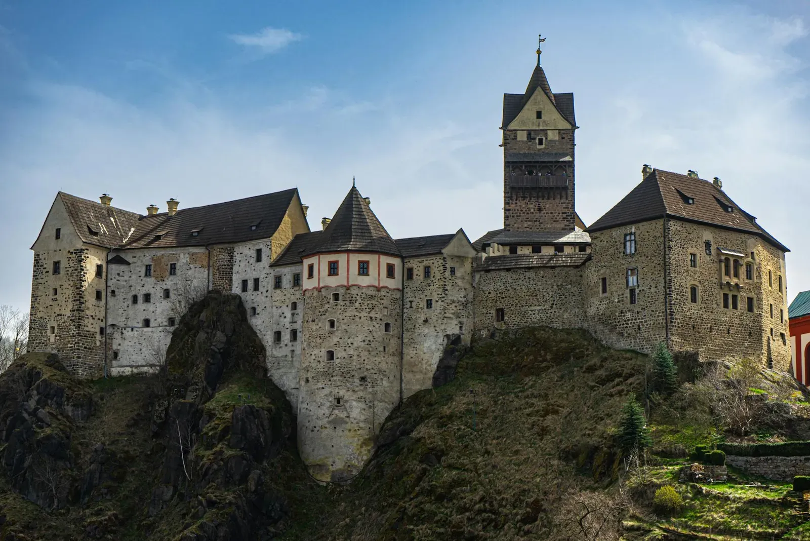 Stunning view of a historic Gothic castle perched on a rocky cliff under a clear sky.