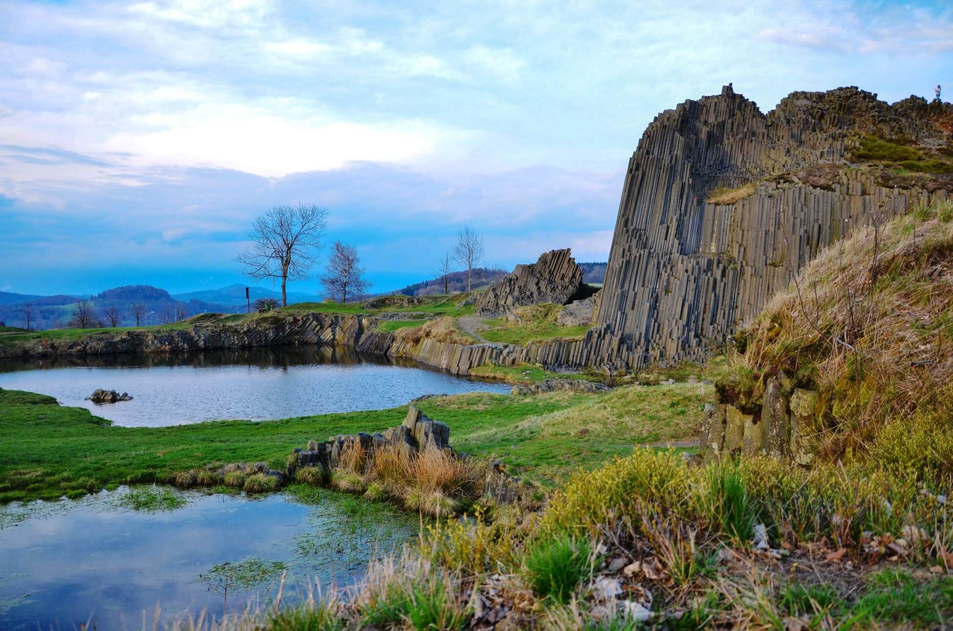 A dramatic, sunlit view of the Czech countryside from a high vantage point, showing two sides of a valley.