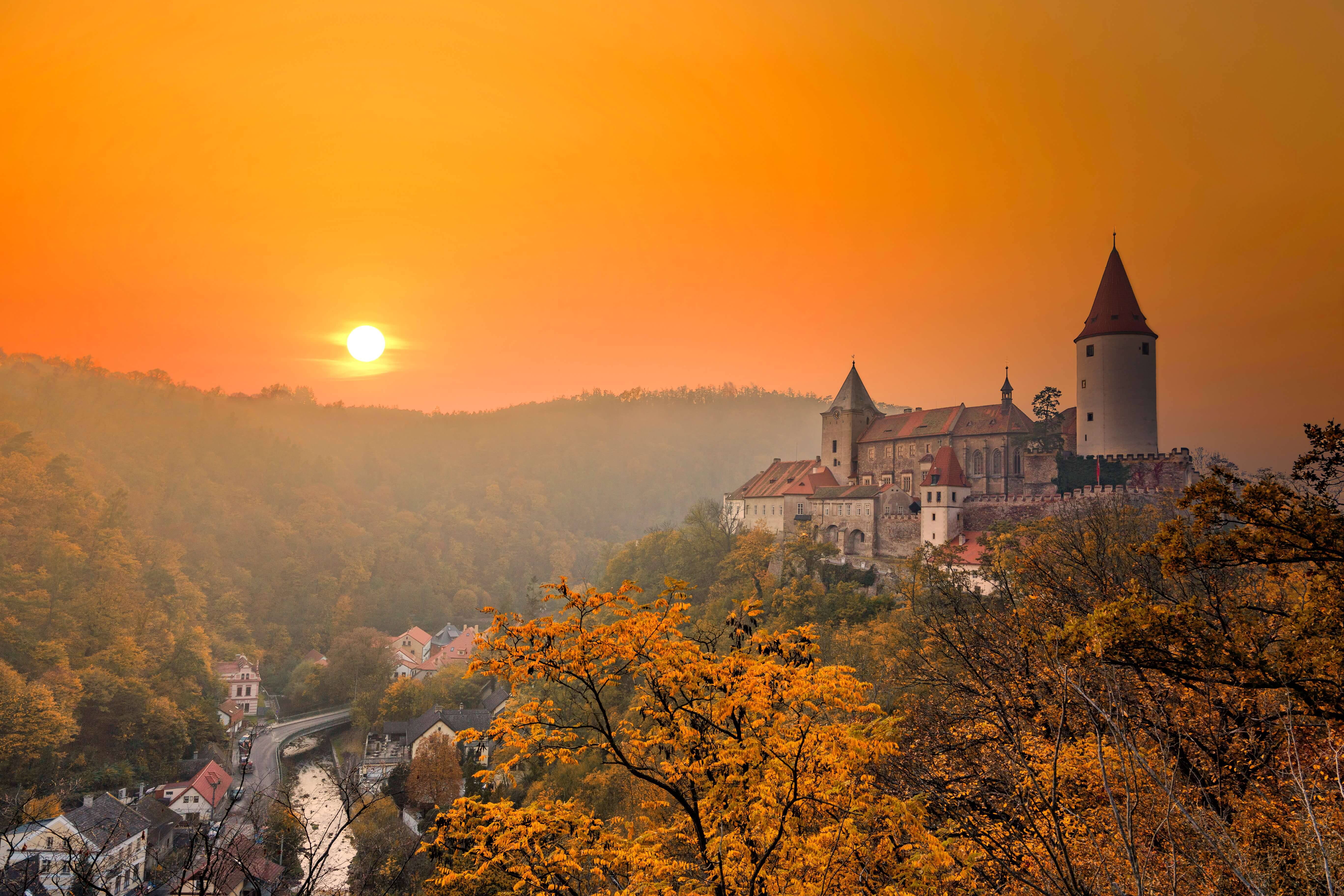 The imposing stone walls and main tower of Křivoklát Castle against a clear blue sky.