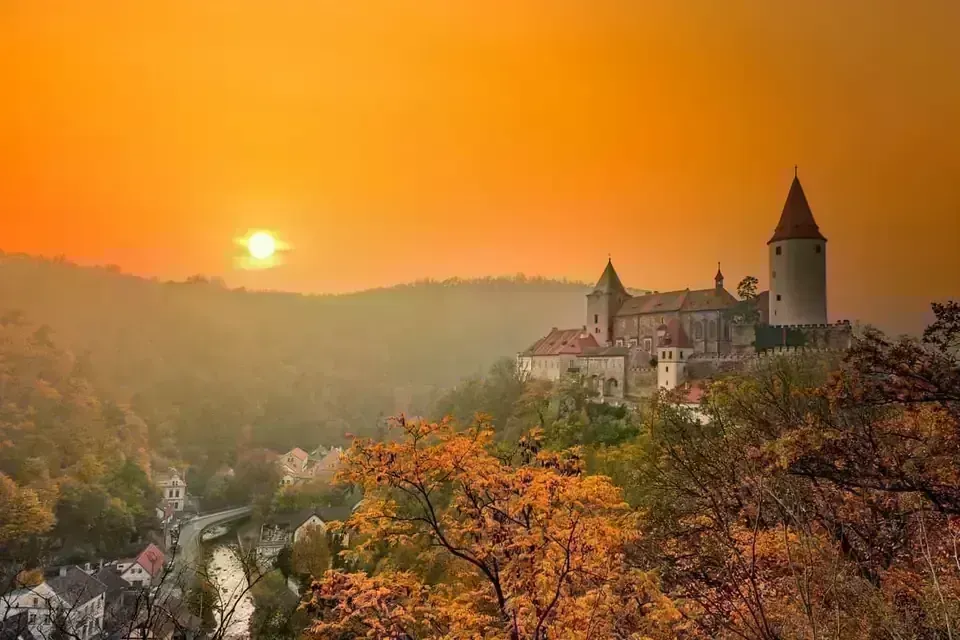 The imposing stone walls and main tower of Křivoklát Castle against a clear blue sky.